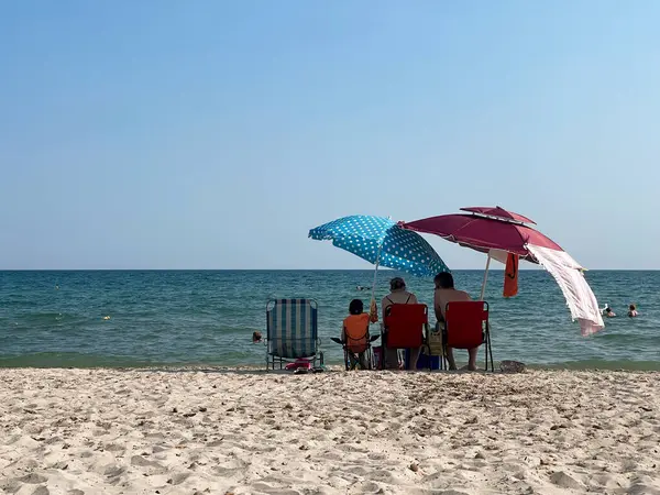 Yaz aile titreşimleri, deniz kenarında güneşli bir günde renkli plaj şemsiyeleri, dinlendirici yaz tatili.