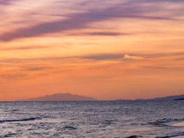 Gün batımı ve deniz manzaraları, dramatik bulutları, sakin dalgaları ve kayalık kıyı şeridi olan güzel gün batımı deniz manzaraları. Okyanus ufkunun manzarası ve doğal akşam ışığı