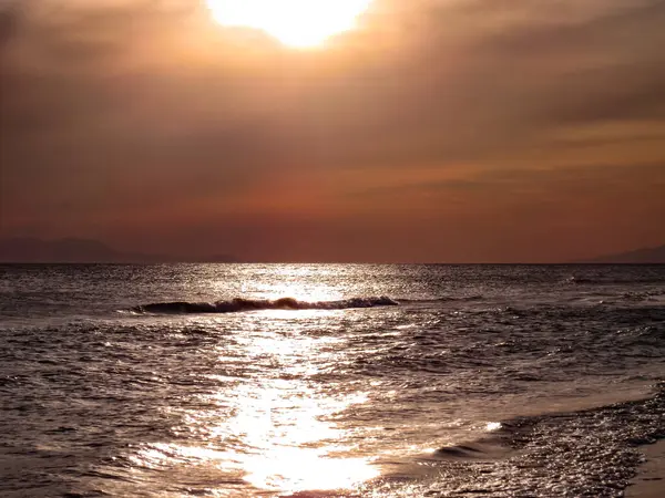 Gün batımı ve deniz manzaraları, dramatik bulutları, sakin dalgaları ve kayalık kıyı şeridi olan güzel gün batımı deniz manzaraları. Okyanus ufkunun manzarası ve doğal akşam ışığı