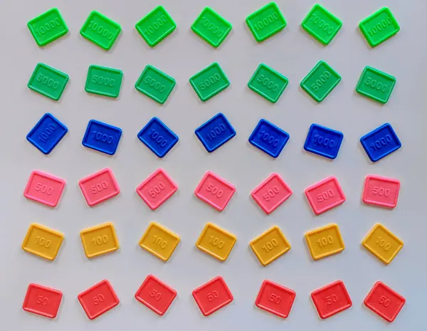 Her biri bir ışık üzerinde sistematik olarak sıralanmış sayısal değerler taşıyan renkli plastik karolardan oluşan bir koleksiyonun yukarıdan aşağıya düz görünümü. Bu fayanslar matematiksel manipülasyonlar, görsel olarak sayıları temsil etmek için tasarlanmış eğitim araçları olarak hizmet vermektedir.