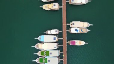 Türkiye 'nin Pier Kemer kentine küçük tekneler yanaştı. İskeleye çok sayıda küçük teknenin yanaştığı huzurlu bir liman sahnesi. Durgun su gökyüzünü yansıtır ve güzel bir kıyı manzarası yaratır. Seyahat, denizcilik ve manzaralı içerik için mükemmel