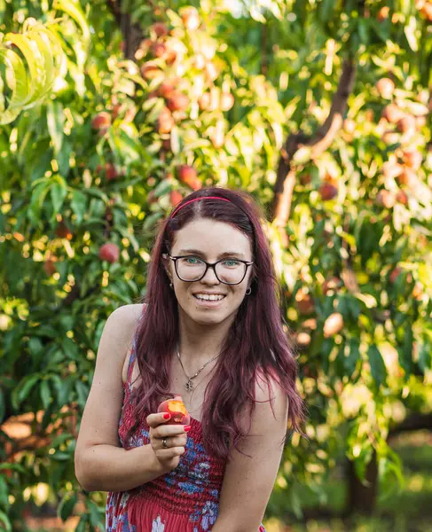 Yazın şeftali bahçesinde gözlüklü bir kız.