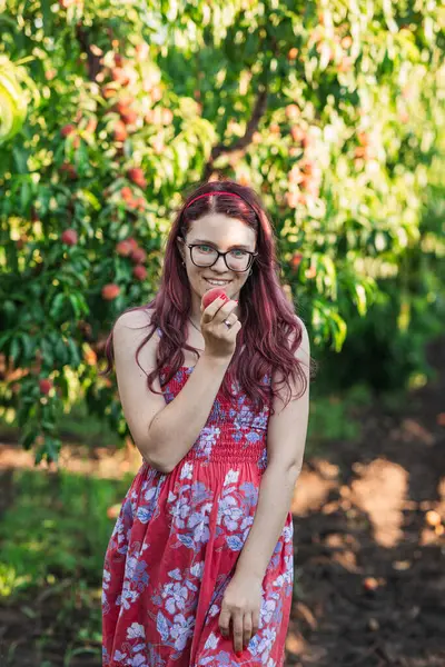 Yazın şeftali bahçesinde gözlüklü bir kız.