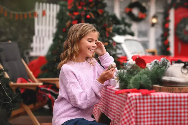 Bahçedeki masada oturan mutlu kız kırmızı retro arabanın arka planında oturuyor.