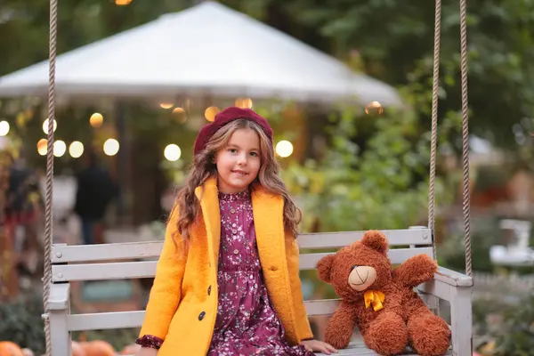 Salıncakta oyuncak ayısı olan kız.