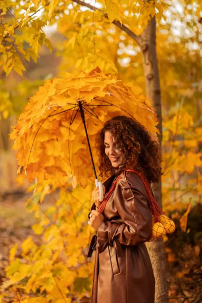 Sonbahar parkında sarı yağmurluklu kadın..