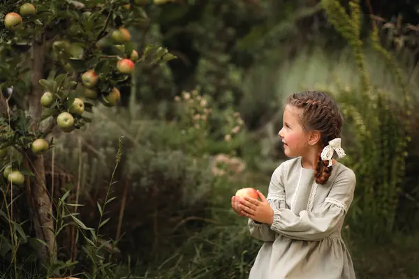 Bir sepet elmalı elbise giymiş küçük kız