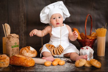 Mutfaktaki masanın üstünde merdanesi olan küçük bir çocuk.