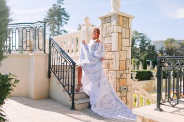 Şık elbiseli güzel bir kız baharda merdivenlerde uzun bir trenle