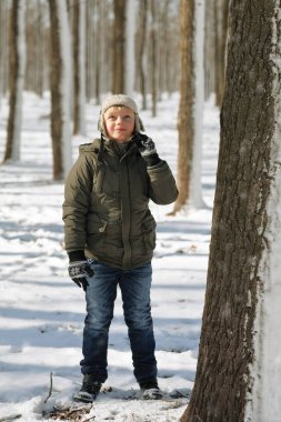 Eski bir ormanda kışlık ceketli bir çocuk.
