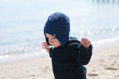 Kumsalda mavi şapkalı küçük bebek.
