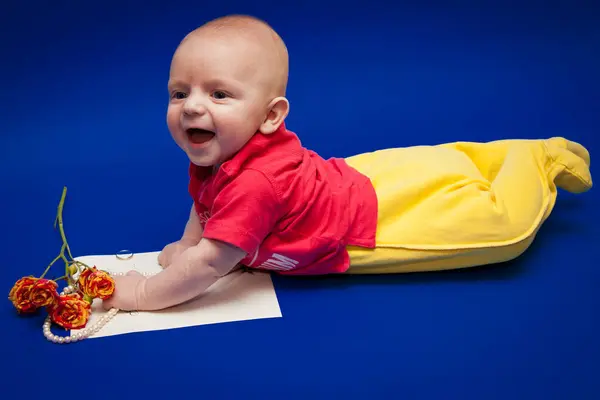 Mavi gömlekli, kırmızı kravatlı, elinde çiçekle arka planda küçük bir çocuk.