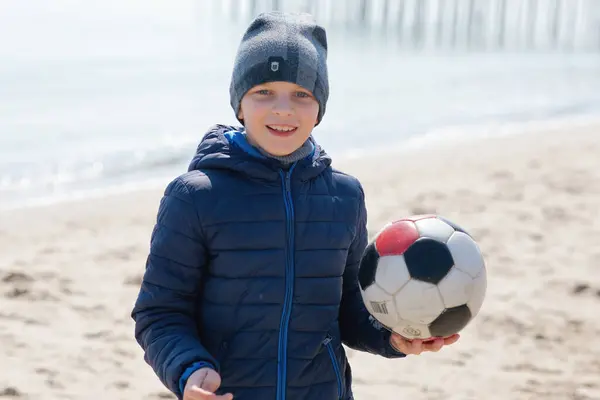 Mutlu çocuk sahilde topla oynuyor.