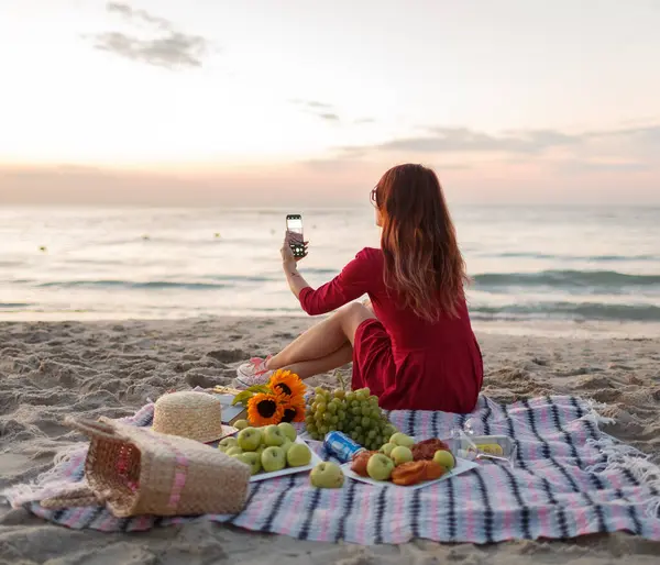 Genç kız şafakta plajda piknikte.