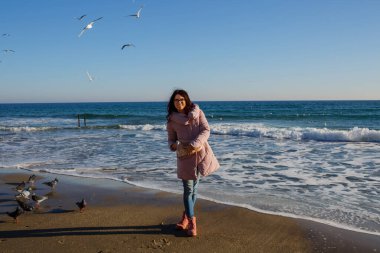 Genç bir kadın sahilde yürüyor.