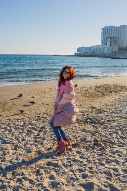 Genç bir kadın sahilde yürüyor.