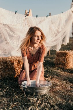 Şapkalı güzel bir kız gün batımında sokakta çamaşır yıkıyor.