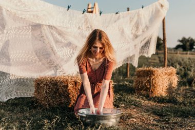 Şapkalı güzel bir kız gün batımında sokakta çamaşır yıkıyor.