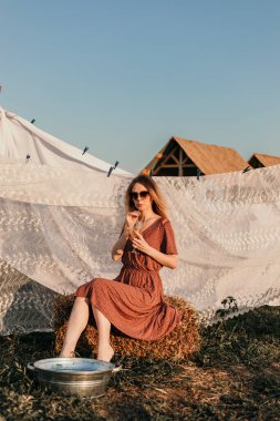 Şapkalı güzel bir kız gün batımında çamaşırlarını yıkıyor.