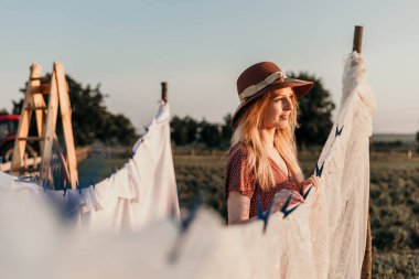 Şapkalı güzel bir kız gün batımında çamaşırlarını yıkıyor.