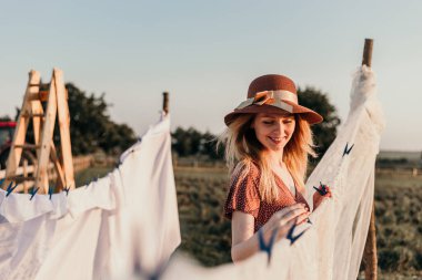Şapkalı güzel bir kız gün batımında çamaşırlarını yıkıyor.