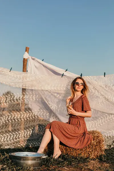 Şapkalı güzel bir kız gün batımında çamaşırlarını yıkıyor.