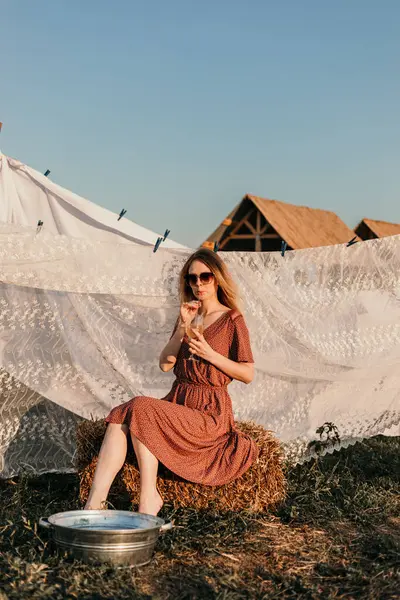 Şapkalı güzel bir kız gün batımında çamaşırlarını yıkıyor.