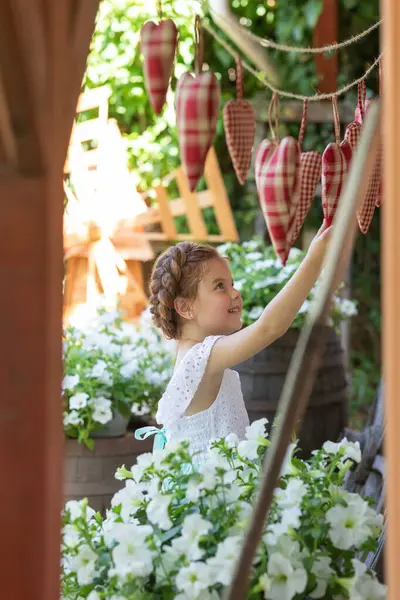 Çiçeklerin arasında kafasında saç örgüsü olan güzel küçük bir kız.