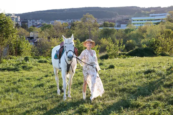 Beyaz bir atın arka planında köpeği olan güzel bir kız..