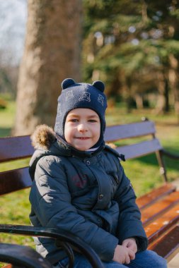 Parktaki bankta oturan küçük çocuk