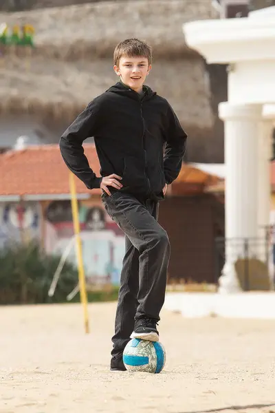 Sokakta futbol oynayan bir çocuk.