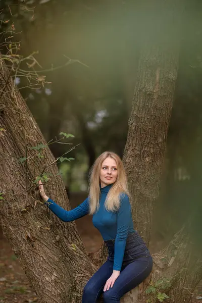 Sonbahar parkında mavi kazaklı sarı saçlı güzel bir genç kız.