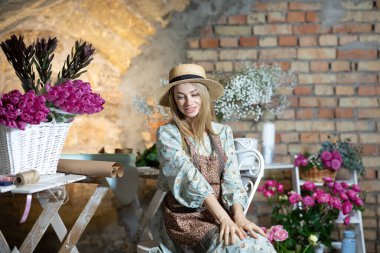 Mavi elbiseli, beyaz saçlı güzel bir kız ve çiçekçi kılığındaki kahverengi önlüklü bir kız.