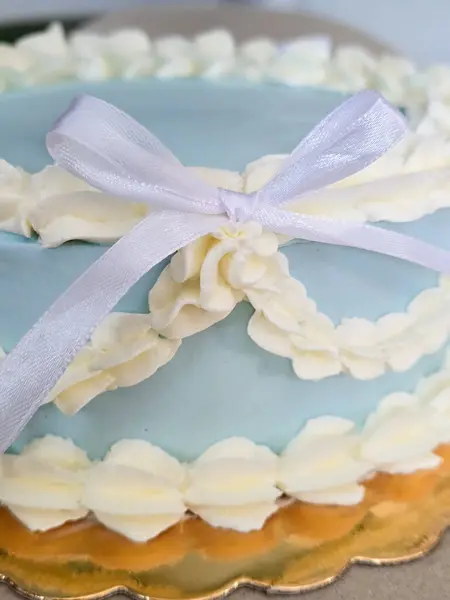 Yan tarafında beyaz kurdeleler olan mavi pasta.