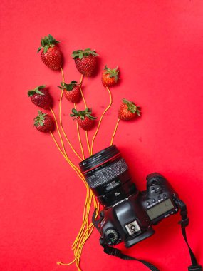 Çilek, çilek ve kırmızı arka planda bir buket gül. düz yatış, üst görünüm.