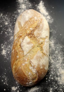 Siyah zemin üzerinde un ile ev yapımı taze ekmek. en üstteki görünüm.