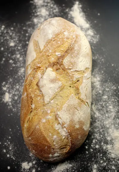 Siyah zemin üzerinde un ile ev yapımı taze ekmek. en üstteki görünüm.