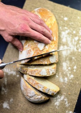 Bıçaklı eller siyah arka planda ev yapımı beyaz çavdar dilimli ekmek. Üst görünüm