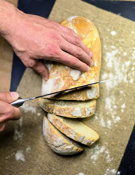Bıçaklı eller siyah arka planda ev yapımı beyaz çavdar dilimli ekmek. Üst görünüm