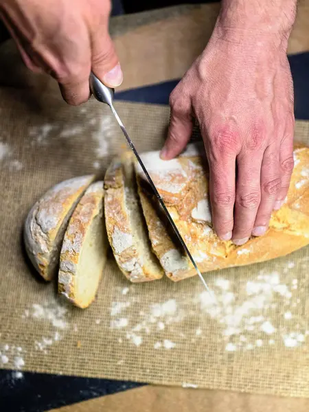Bıçaklı eller siyah arka planda ev yapımı beyaz çavdar dilimli ekmek. Üst görünüm