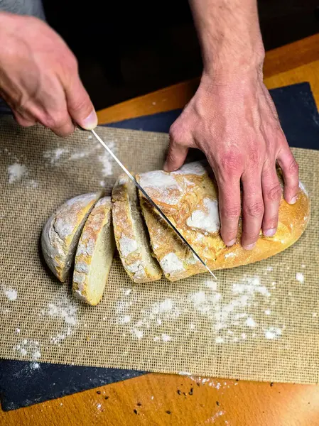 Bıçaklı eller siyah arka planda ev yapımı beyaz çavdar dilimli ekmek. Üst görünüm