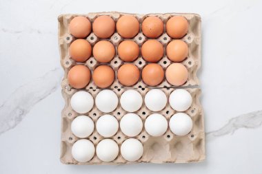 Beyaz arka planda kağıttan yumurta tepsisi içinde renkli tavuk yumurtalarının yakın çekimi. Karton tepside bir grup taze beyaz yumurta. Organik gıda doğası gereği sağlıklıdır.