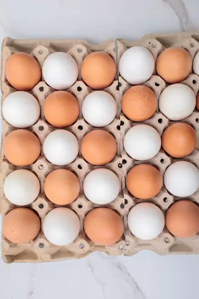 Beyaz arka planda kağıttan yumurta tepsisi içinde renkli tavuk yumurtalarının yakın çekimi. Karton tepside bir grup taze beyaz yumurta. Organik gıda doğası gereği sağlıklıdır.