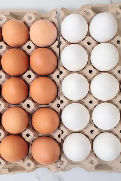 Beyaz arka planda kağıttan yumurta tepsisi içinde renkli tavuk yumurtalarının yakın çekimi. Karton tepside bir grup taze beyaz yumurta. Organik gıda doğası gereği sağlıklıdır.
