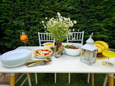 Bahçeli beyaz masa ve vazolu beyaz papatyalar.