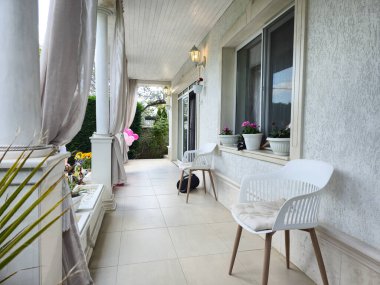 Beyaz sandalyeli ve palmiyeli güzel bir evin verandası.