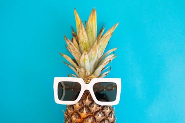 Mavi arkaplanda güneş gözlüklü yaratıcı ananas, yaz sahili tasarım şablonu, kopyalama alanı, metin için yakın plan, boş boşluk