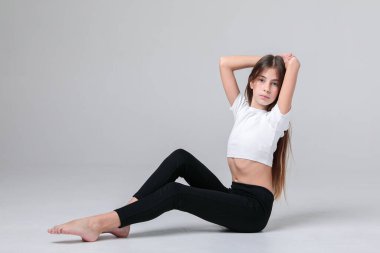 Siyah taytlı, uzun saçlı ve beyaz arka planda fotoğraf stüdyosunun tepesinde güzel bir genç kız. Modellik. Fotoğraf mankeni. Fotoşop. Fotoğraf stüdyosu