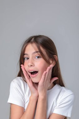 Siyah taytlı uzun saçlı güzel bir genç kızın portresi ve beyaz arka planda bir fotoğraf stüdyosunun kapağı. Farklı duygular. Duygusal bir çekim. Modellik. Fotoğraf mankeni. Fotoğraf oturumu.