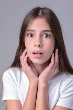 Siyah taytlı uzun saçlı güzel bir genç kızın portresi ve beyaz arka planda bir fotoğraf stüdyosunun kapağı. Farklı duygular. Duygusal bir çekim. Modellik. Fotoğraf mankeni. Fotoğraf oturumu.